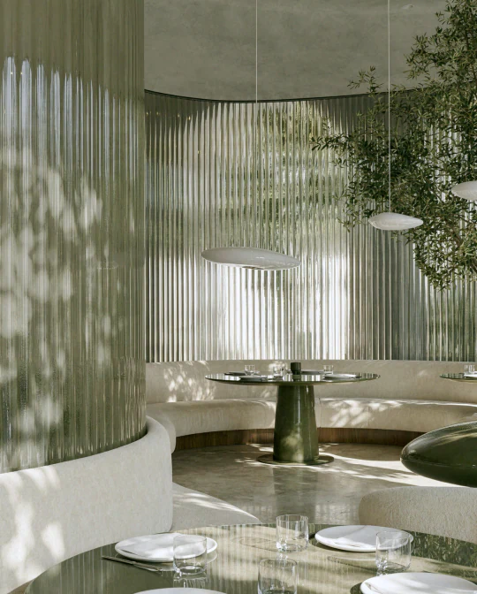 A finished option open in the app: a restaurant room walled in fluted green glass, with a curved banquette around a stone table.